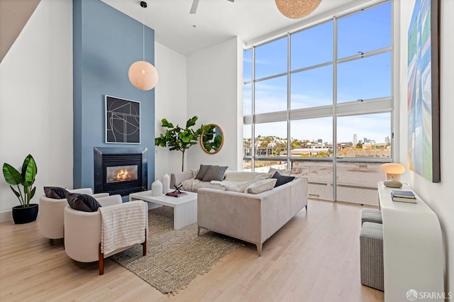1099 23rd St Unit 18, San Francisco, CA 94107 - living area featuring a wall of windows, a high ceiling, light wood-style floors, ceiling fan, and a glass covered fireplace