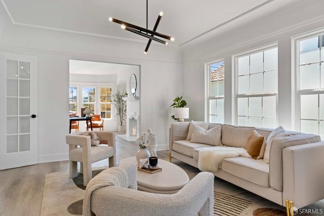 living area with baseboards, an inviting chandelier, and wood finished floors