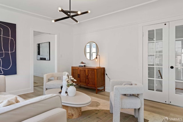 living area with baseboards, a chandelier, and light wood finished floors