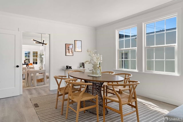 dining room with light wood finished floors, baseboards, and ornamental molding