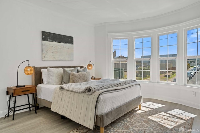 bedroom with ornamental molding, baseboards, and wood finished floors