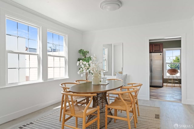 dining room featuring light wood-type flooring, baseboards, and crown molding
