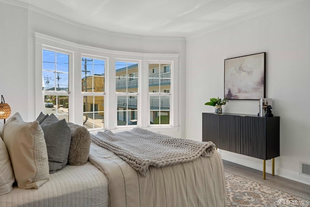 bedroom with crown molding, wood finished floors, baseboards, and visible vents