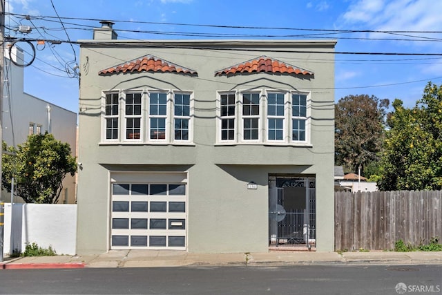 view of front of home with an attached garage, a fenced front yard, and stucco siding