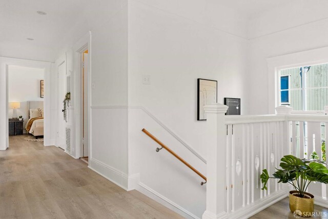hall featuring light wood-type flooring and an upstairs landing