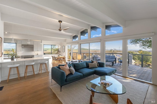 living room featuring light wood-style floors, vaulted ceiling with beams, and ceiling fan