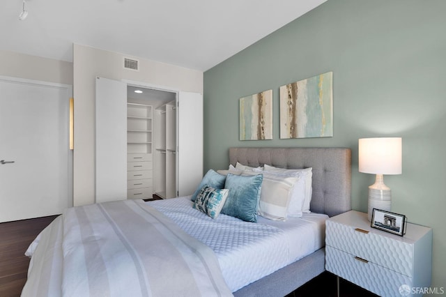 bedroom featuring dark wood-type flooring, a closet, and a walk in closet