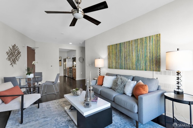 living room featuring dark wood-type flooring and ceiling fan