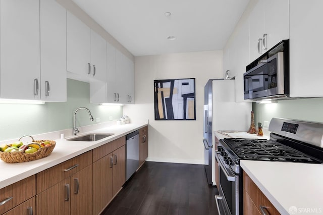 kitchen with white cabinets, stainless steel appliances, sink, and dark hardwood / wood-style flooring