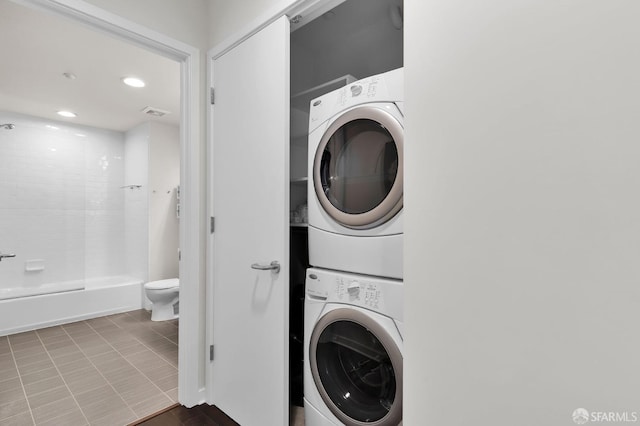 washroom featuring stacked washing maching and dryer and light tile patterned floors