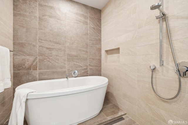 full bath with a freestanding tub and tile walls