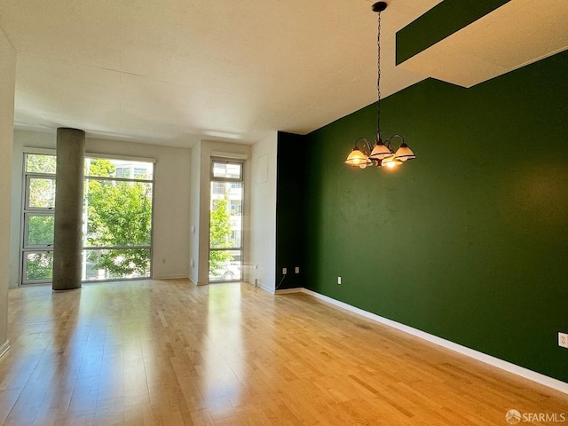 empty room featuring a notable chandelier and hardwood / wood-style flooring