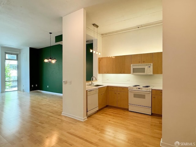 kitchen with light hardwood / wood-style flooring, hanging light fixtures, sink, and white appliances