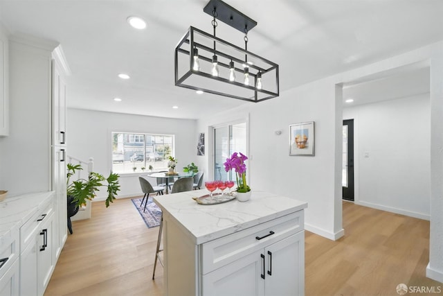 3901 La Colina Rd, El Sobrante, CA 94803 - kitchen with light wood-type flooring, a kitchen island, white cabinets, recessed lighting, and a breakfast bar area