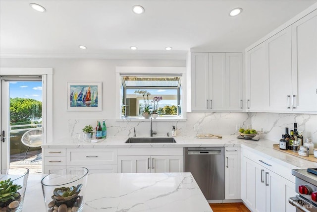 kitchen with stainless steel appliances, a sink, white cabinetry, and decorative backsplash