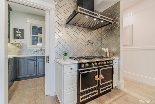 kitchen featuring light countertops, range with two ovens, ventilation hood, and light wood-style flooring
