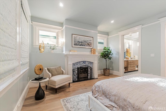 bedroom with multiple windows, a fireplace, recessed lighting, and light wood-style flooring