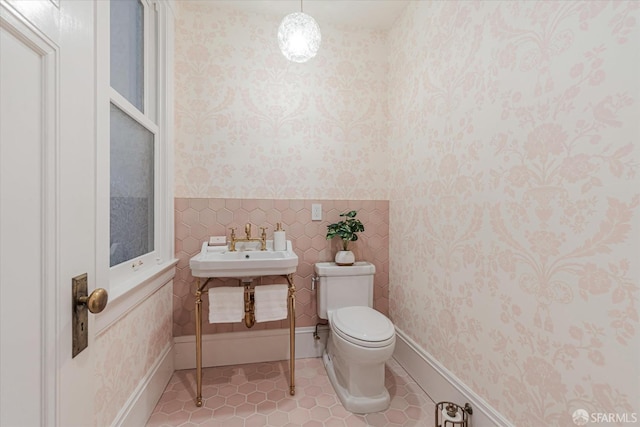 half bath featuring wainscoting, a sink, tile patterned flooring, toilet, and wallpapered walls