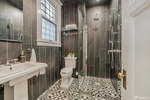 full bath with a sink, a stall shower, toilet, and tile walls