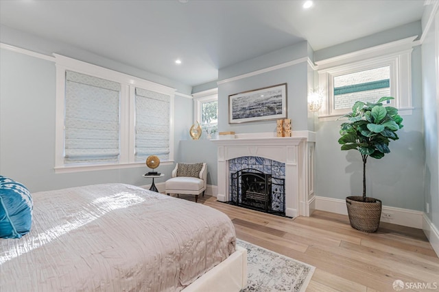 bedroom with recessed lighting, baseboards, wood finished floors, and a fireplace