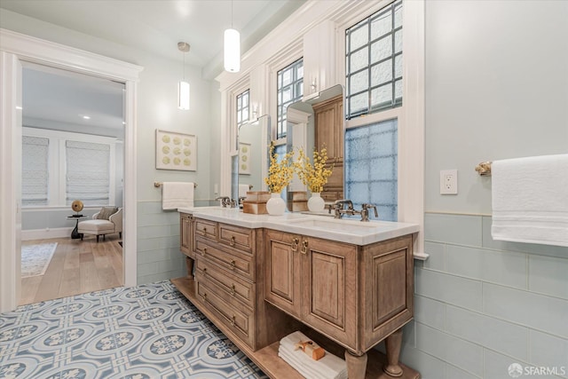 full bath with a sink, tile walls, wainscoting, and double vanity
