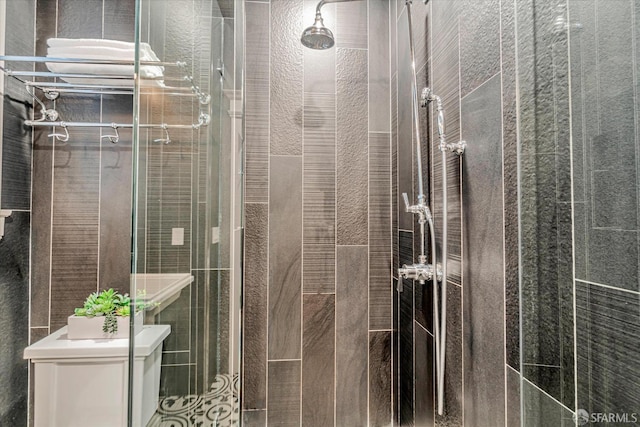 full bathroom with tile walls, a stall shower, and toilet