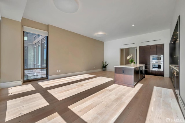 288 Pacific Ave Unit 4E, San Francisco, CA 94111 - kitchen featuring double oven, a center island, light countertops, light wood-type flooring, and dark brown cabinetry