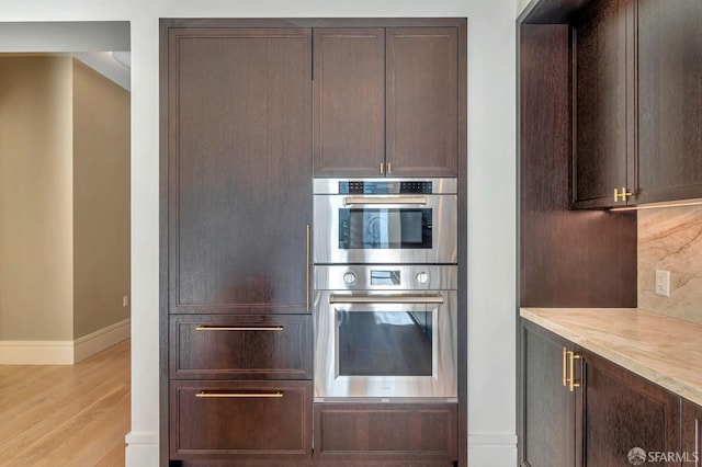288 Pacific Ave Unit 4E, San Francisco, CA 94111 - kitchen with baseboards, stainless steel double oven, light wood-type flooring, dark brown cabinets, and decorative backsplash