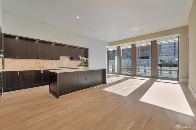 288 Pacific Ave Unit 4E, San Francisco, CA 94111 - kitchen with light countertops, backsplash, light wood-style floors, dark brown cabinetry, and a kitchen island