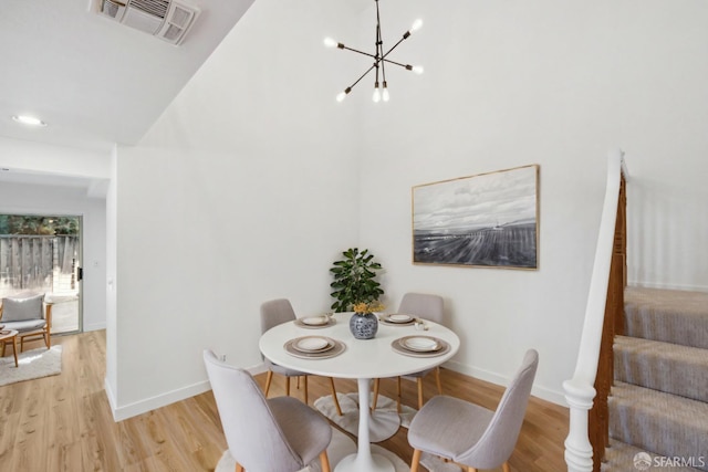 dining room featuring visible vents, light wood-style floors, baseboards, high vaulted ceiling, and a chandelier