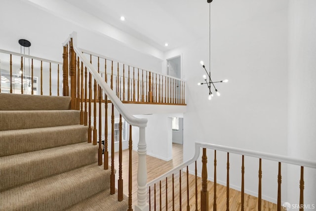 stairs featuring a high ceiling, a notable chandelier, recessed lighting, baseboards, and wood finished floors
