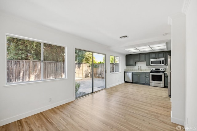 kitchen featuring appliances with stainless steel finishes, light countertops, light wood-style flooring, baseboards, and visible vents