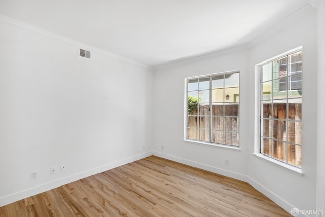 empty room with baseboards, ornamental molding, light wood finished floors, and visible vents