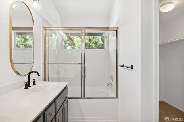 full bathroom featuring vanity, a walk in closet, and shower / bath combination with glass door