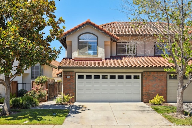 mediterranean / spanish-style house with brick siding, a tile roof, and concrete driveway