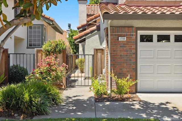view of exterior entry featuring brick siding, fence, a gate, and stucco siding
