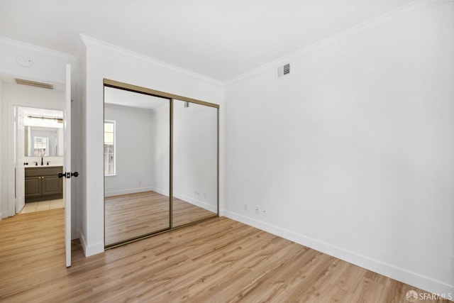 unfurnished bedroom with visible vents, ornamental molding, light wood-style flooring, and baseboards