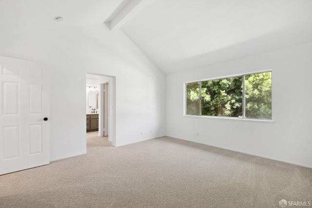 unfurnished bedroom featuring beam ceiling, light carpet, baseboards, high vaulted ceiling, and ensuite bath