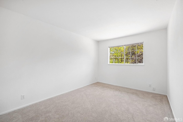 carpeted empty room featuring baseboards