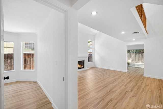 unfurnished living room with visible vents, a brick fireplace, baseboards, recessed lighting, and light wood-type flooring