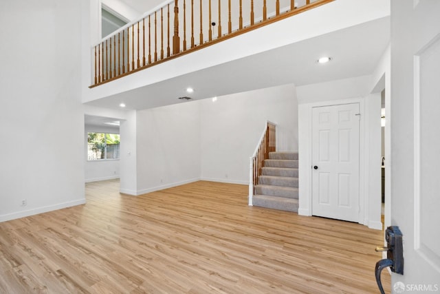 unfurnished living room with baseboards, a high ceiling, stairs, and wood finished floors