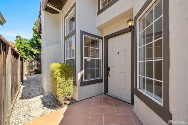 doorway to property featuring fence and stucco siding