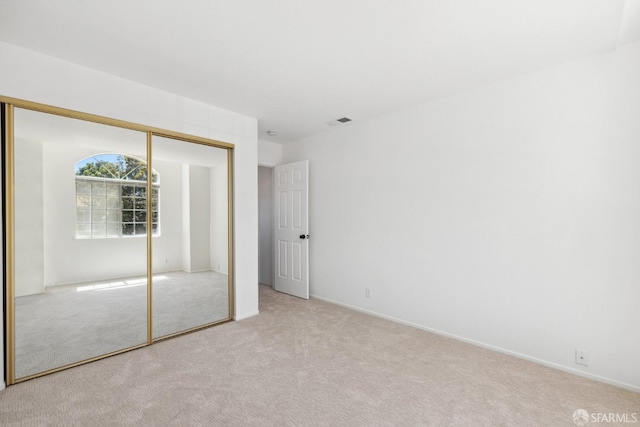 unfurnished bedroom with baseboards, visible vents, carpet, and a closet