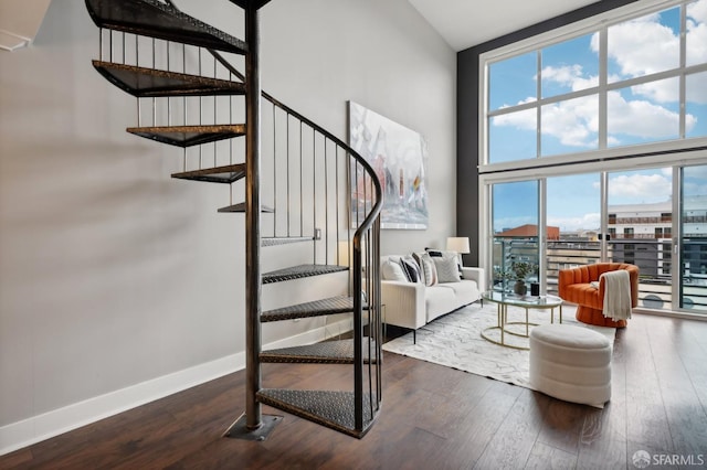 stairs featuring a towering ceiling, wood-type flooring, and a wall of windows