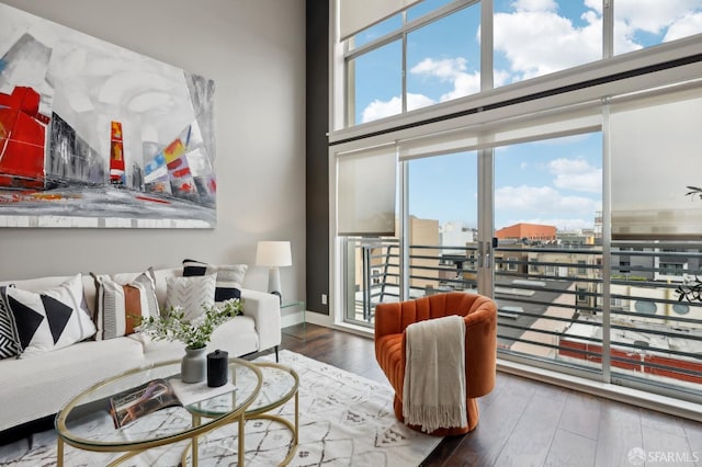 living room with plenty of natural light, dark wood-type flooring, and a towering ceiling