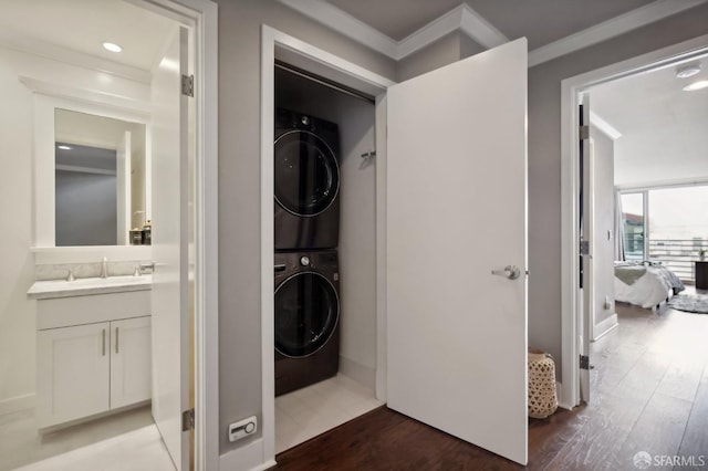 laundry room with stacked washer / drying machine, dark hardwood / wood-style floors, and sink