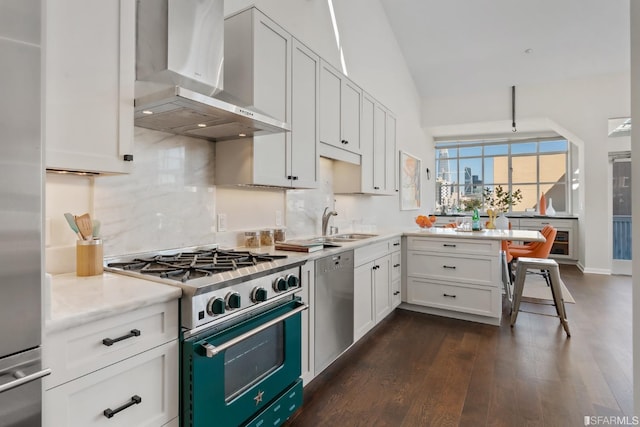 kitchen featuring wall chimney range hood, vaulted ceiling, dark hardwood / wood-style floors, appliances with stainless steel finishes, and white cabinetry