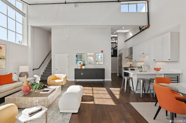 living room featuring a high ceiling, dark hardwood / wood-style floors, wine cooler, and plenty of natural light