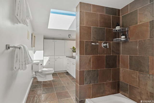 bathroom featuring a tile shower, vanity, and toilet