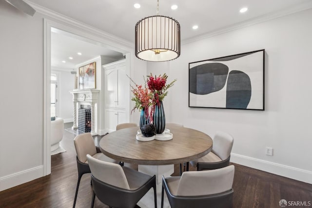 dining area with baseboards, dark wood finished floors, a high end fireplace, and crown molding